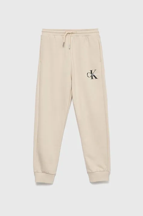 Calvin Klein Jeans spodnie dresowe bawełniane dziecięce kolor beżowy z nadrukiem