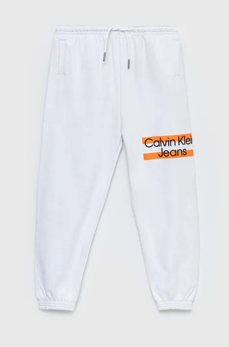 Detské bavlnené tepláky Calvin Klein Jeans biela farba, s potlačou