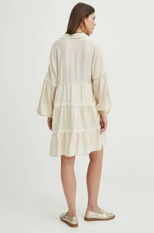Šaty dámske mini s ozdobnými prvkami béžová farba <p>Hlavný materiál: 85 % Viskóza, 15 % Polyamid Podšívka: 100 % Viskóza</p>