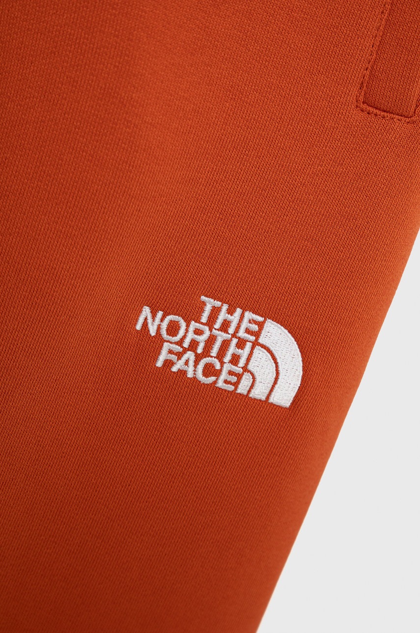

Детские хлопковые брюки The North Face цвет оранжевый с аппликацией
