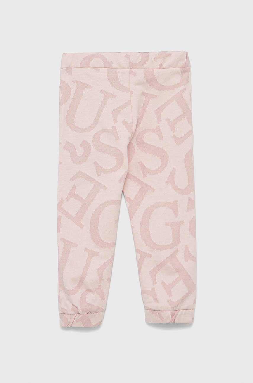 

Детские хлопковые брюки Guess цвет розовый с аппликацией