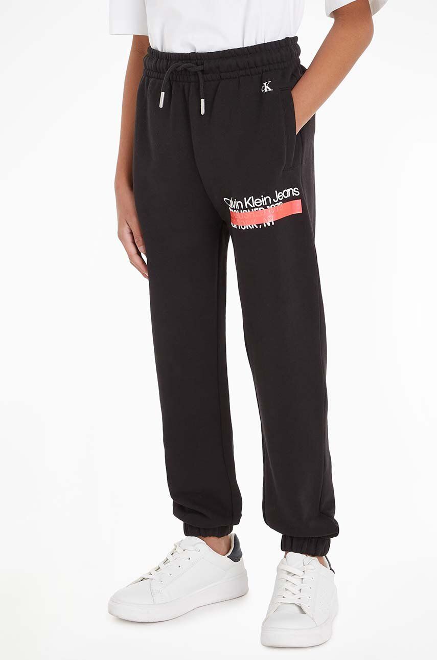 E-shop Dětské bavlněné tepláky Calvin Klein Jeans černá barva, s potiskem