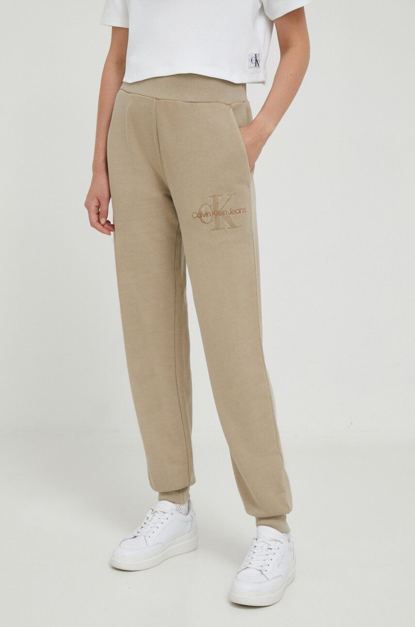 Levně Bavlněné tepláky Calvin Klein Jeans béžová barva