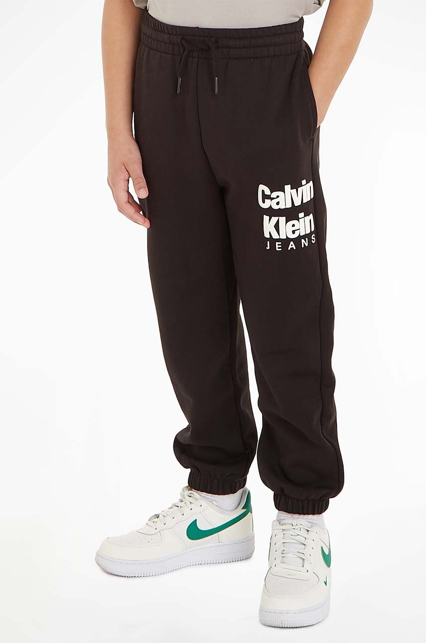Levně Dětské tepláky Calvin Klein Jeans černá barva, s potiskem