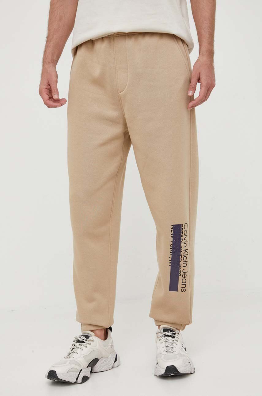 Tepláky Calvin Klein Jeans béžová barva, s potiskem - béžová -  73 % Bavlna