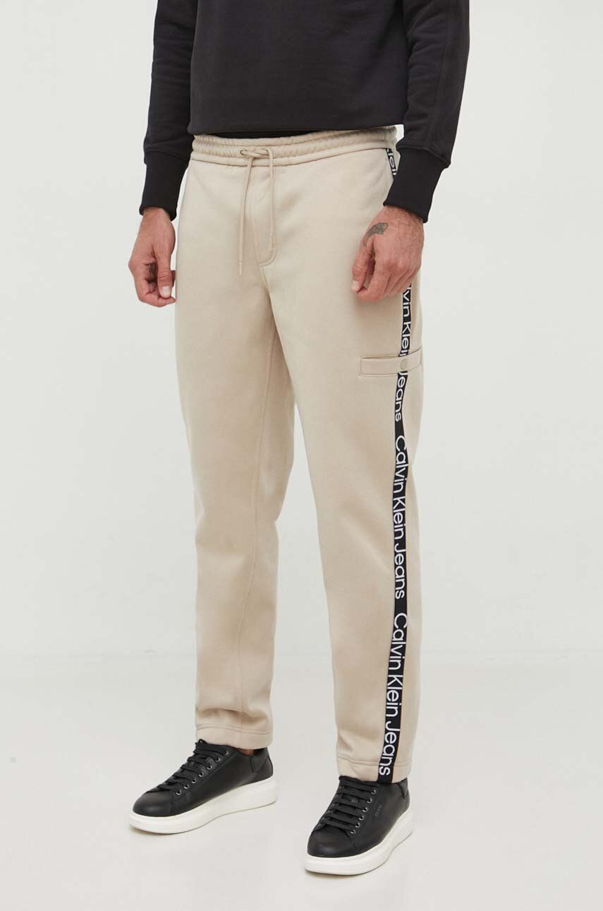 Levně Tepláky Calvin Klein Jeans béžová barva, s aplikací