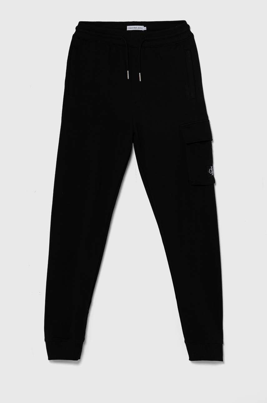 Levně Dětské bavlněné tepláky Calvin Klein Jeans BADGE CARGO RELAXED černá barva, IB0IB02199