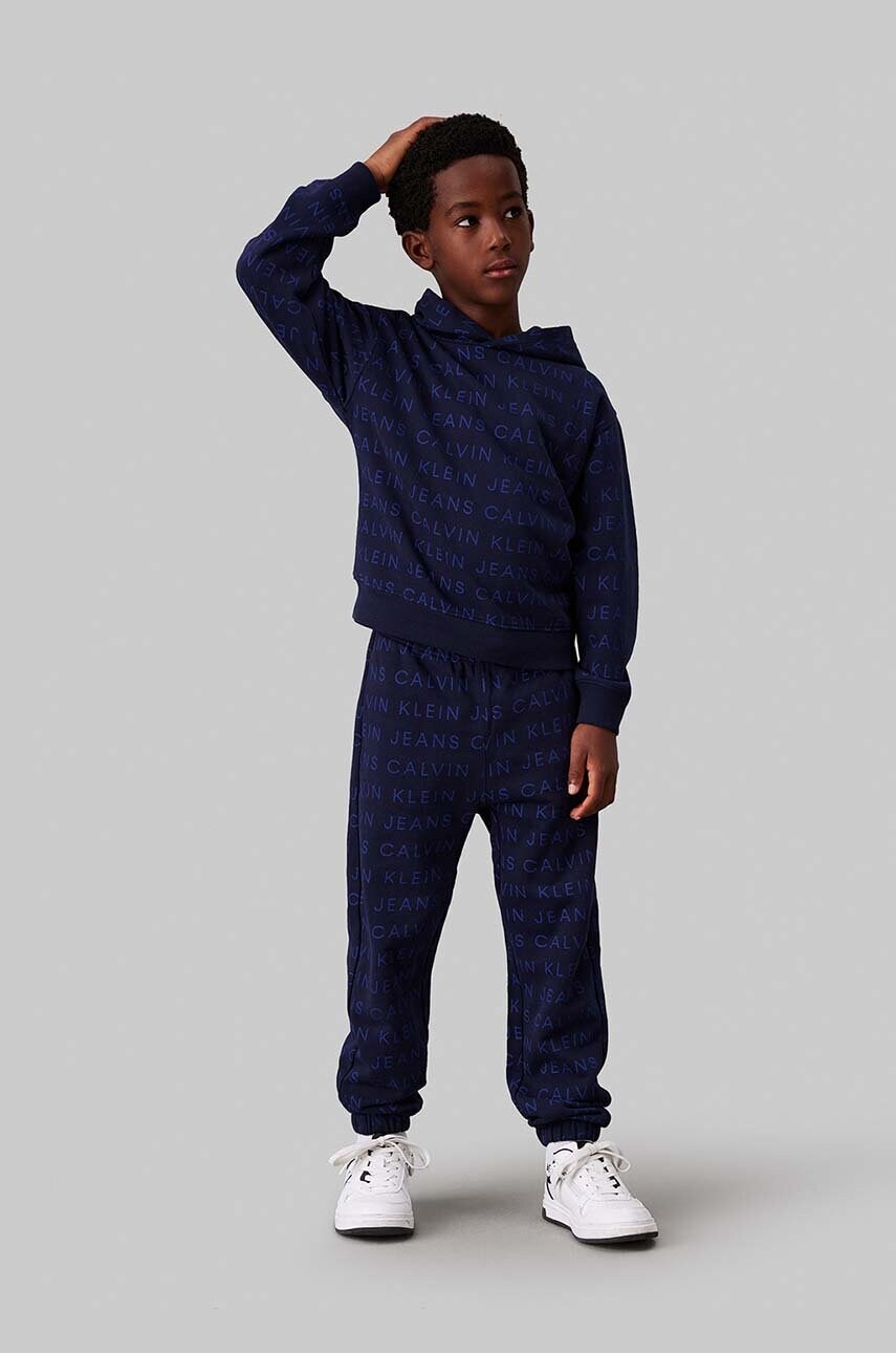 Levně Dětské bavlněné tepláky Calvin Klein Jeans AOP JOGGER tmavomodrá barva, IB0IB02323