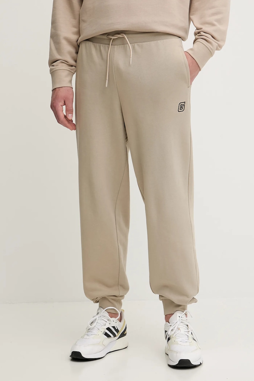 Levně Bavlněné tepláky Guess MENTORE pánské, béžová barva, Z5YB01 KCE91