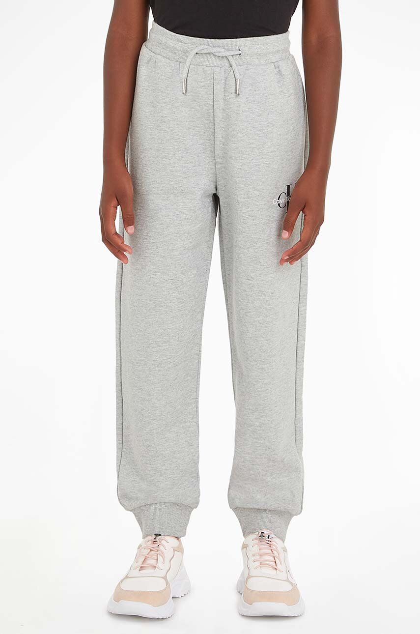 Levně Dětské bavlněné tepláky Calvin Klein Jeans šedá barva, s potiskem