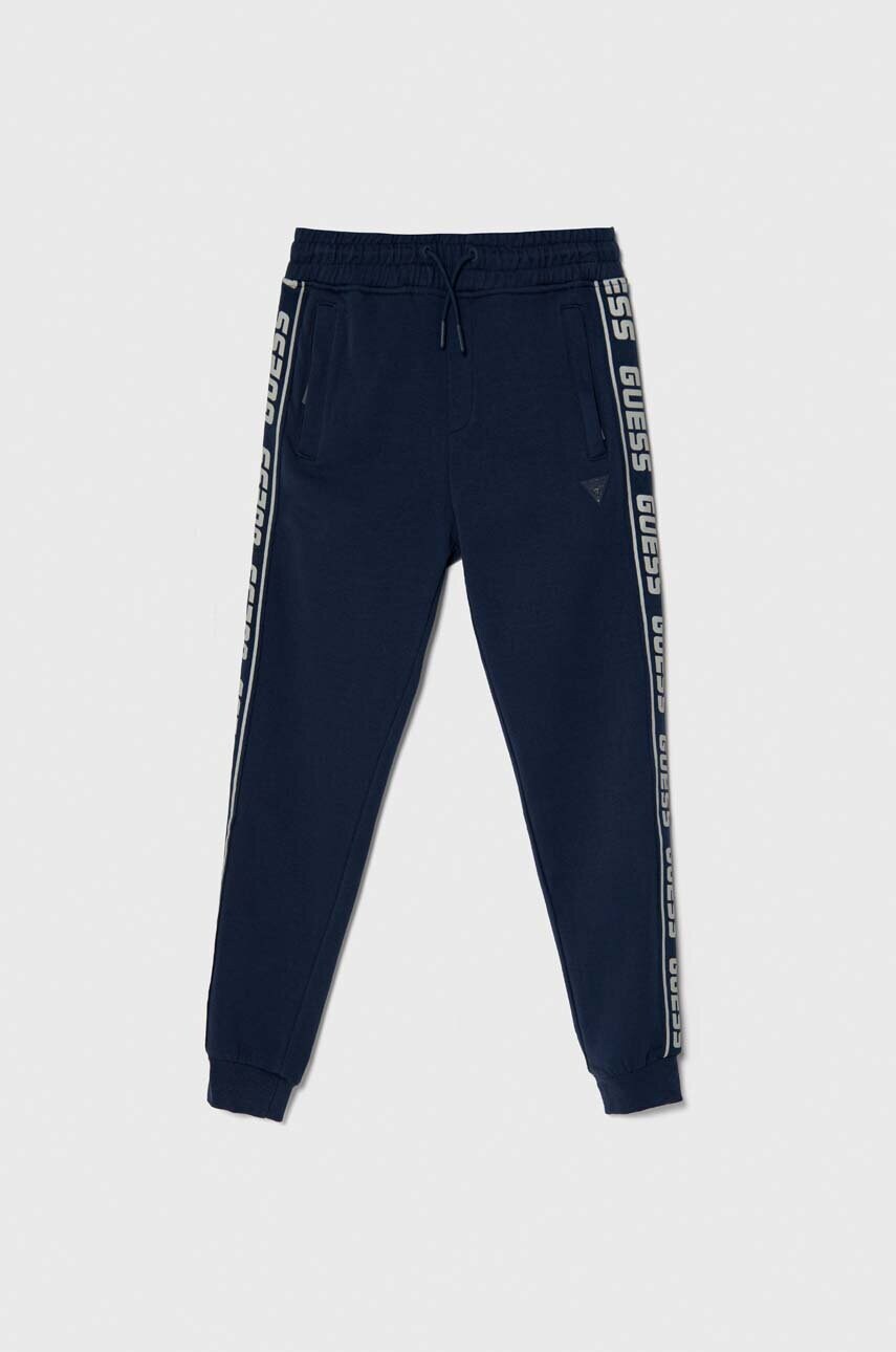 Levně Dětské tepláky Guess tmavomodrá barva, s potiskem