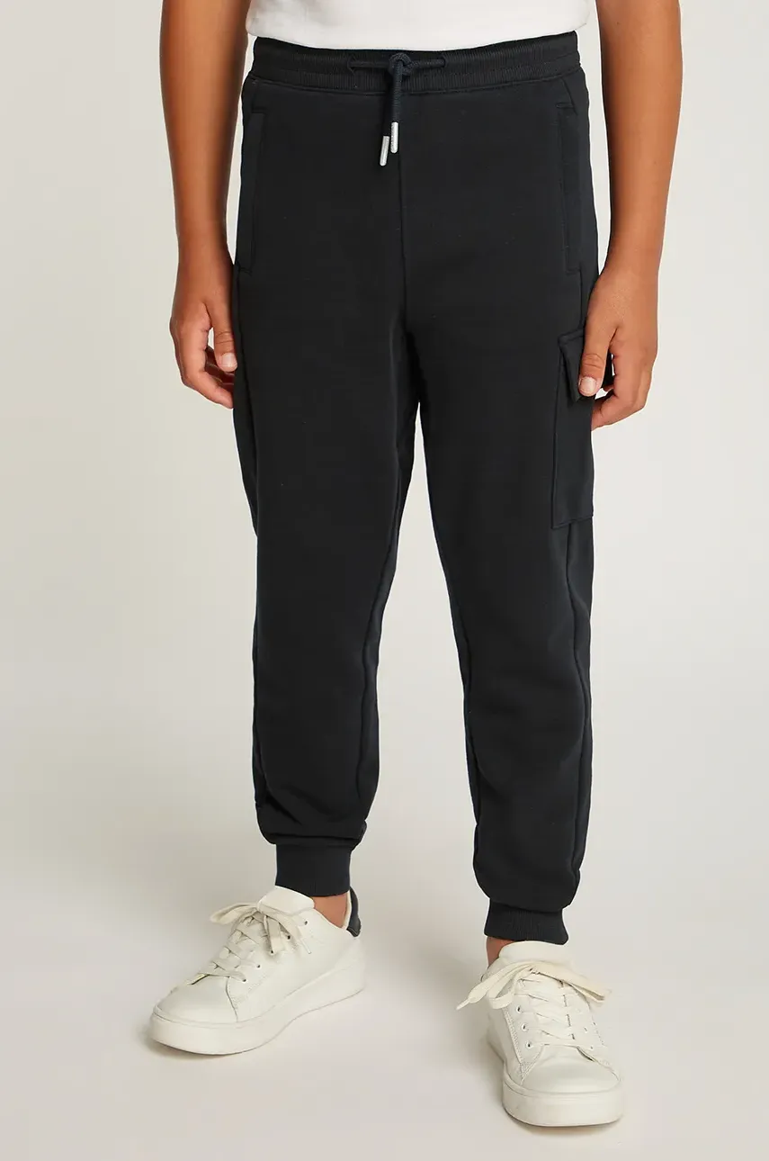 Levně Dětské bavlněné tepláky Calvin Klein Jeans RELAXED TAPERED LEG CARGO černá barva, IB0IB02409