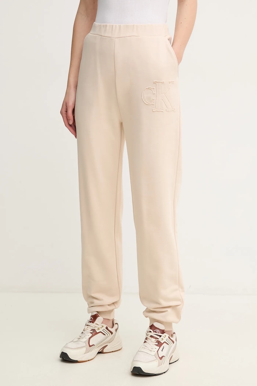 Levně Bavlněné tepláky Calvin Klein Jeans béžová barva, s aplikací, J20J225355