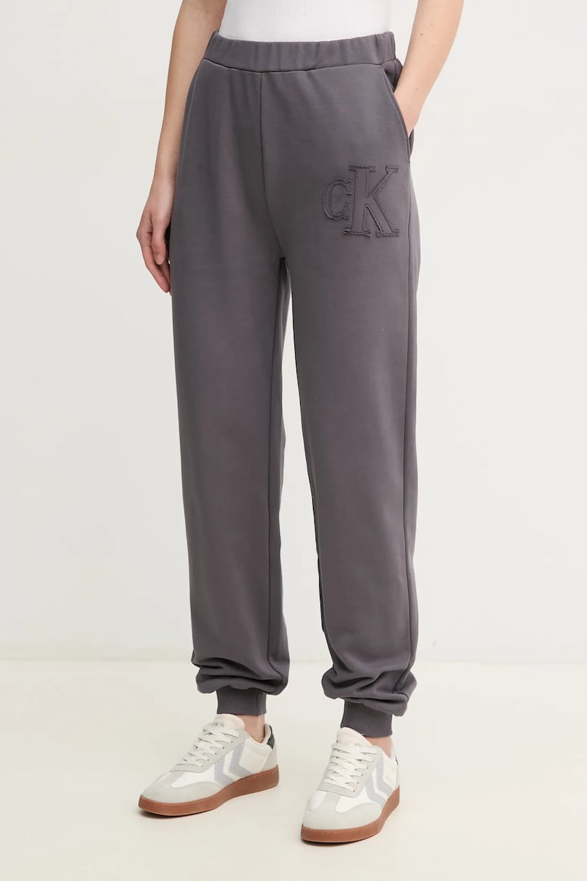 Levně Bavlněné tepláky Calvin Klein Jeans šedá barva, s aplikací, J20J225355