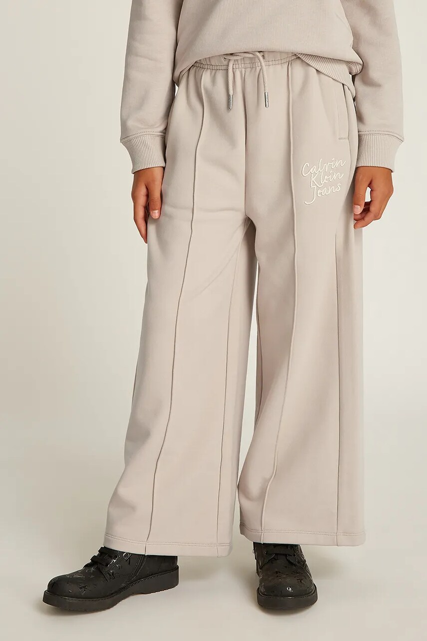 Levně Dětské tepláky Calvin Klein Jeans HANDW LOGO WIDE béžová barva, hladké, IG0IG02775